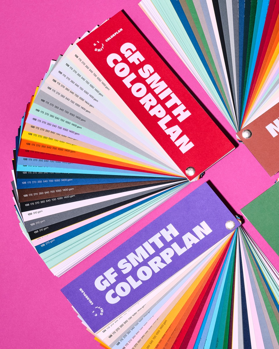 Open Colorplan-kleurenwaaiers op een felroze achtergrond